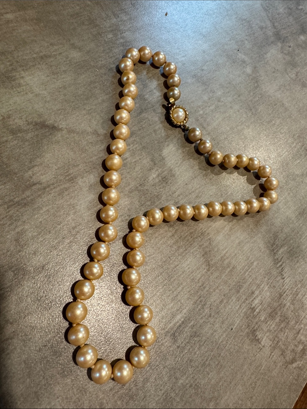 vintage faux pearl necklace featuring champ -colored beads and a gold-tone clasp